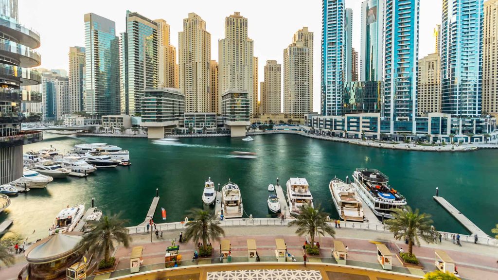 Dubai marina with modern buildings and traditional boat timelapse